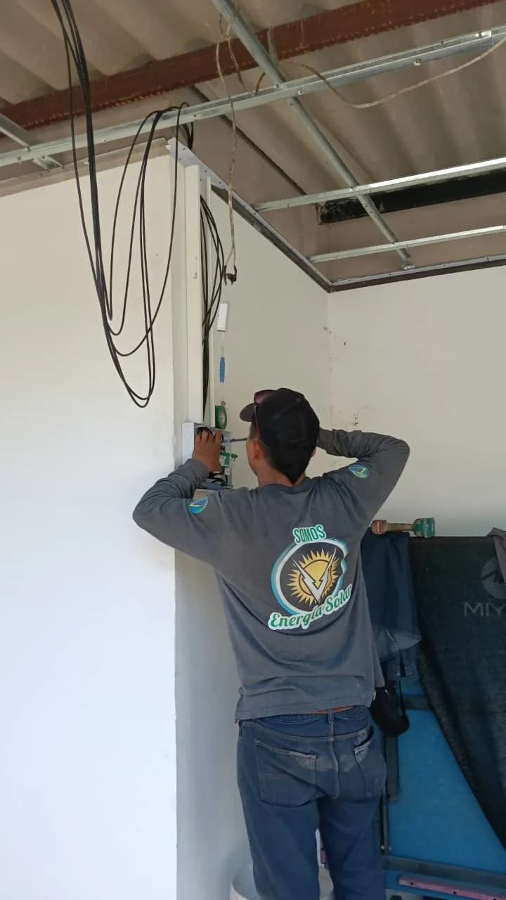 Técnico de la cuadrilla instalando el tablero y la canalización eléctrica sobre el muro, con el cableado ya tendido bajo la cubierta.