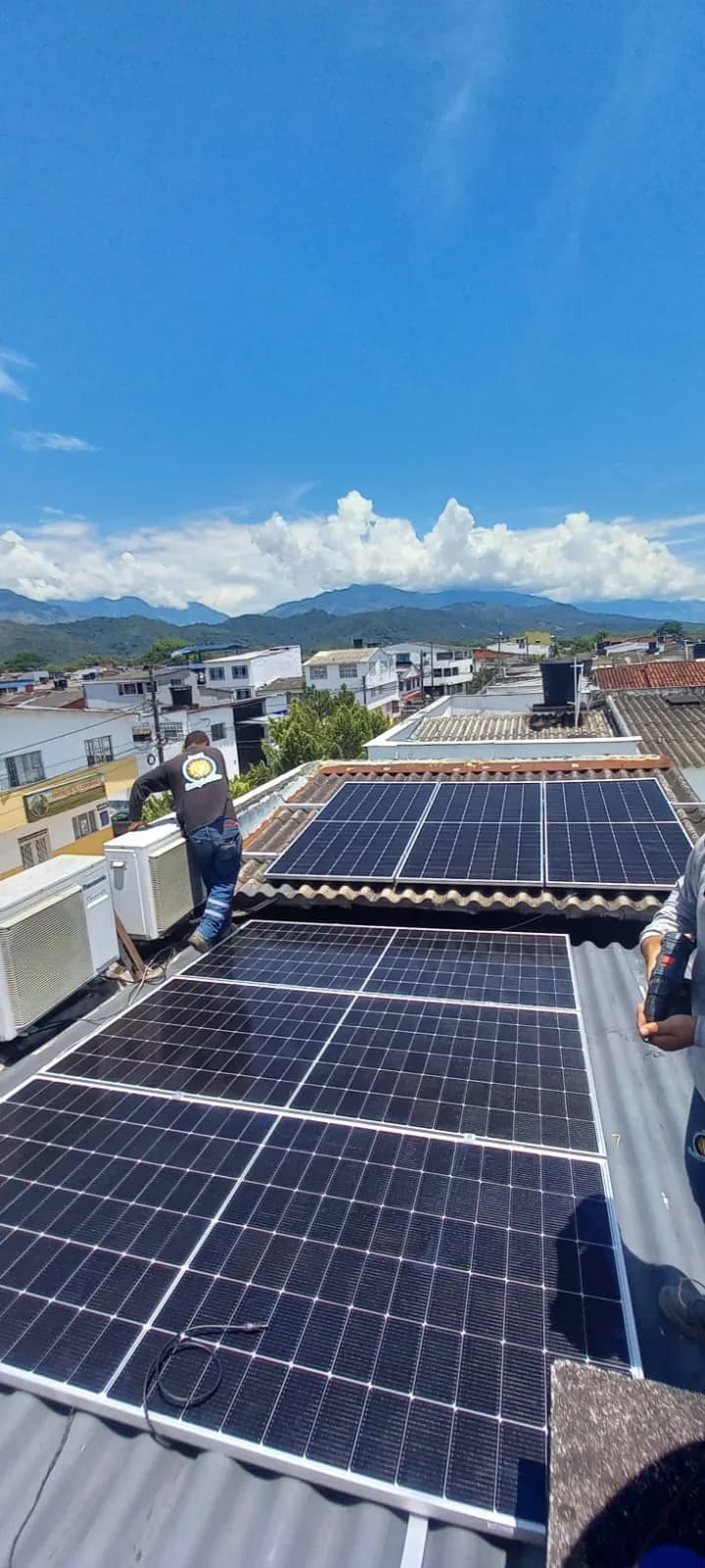 Vista del sistema instalado desde el alero de teja, con los módulos de la cubierta baja y el paisaje urbano de la ciudad.