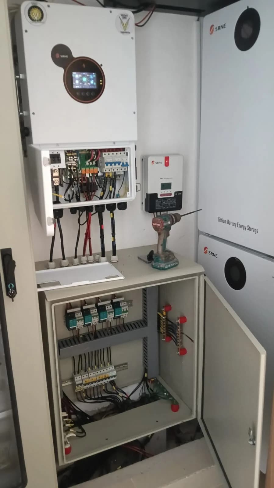 Cuarto técnico con el inversor híbrido SRNE, el controlador de carga MPPT, los tableros de protección DC/AC y dos módulos de baterías de litio.