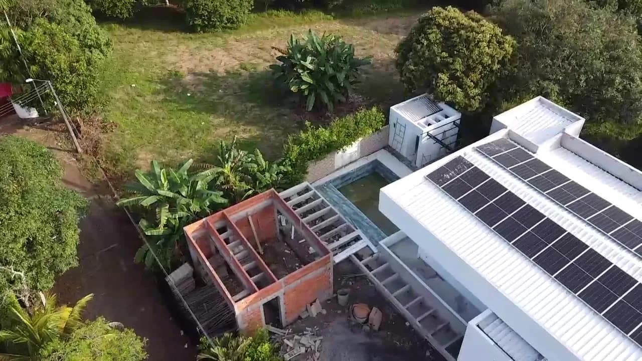 Composición diagonal desde el dron con los módulos ocupando la cubierta metálica y la piscina y la obra gris al costado.