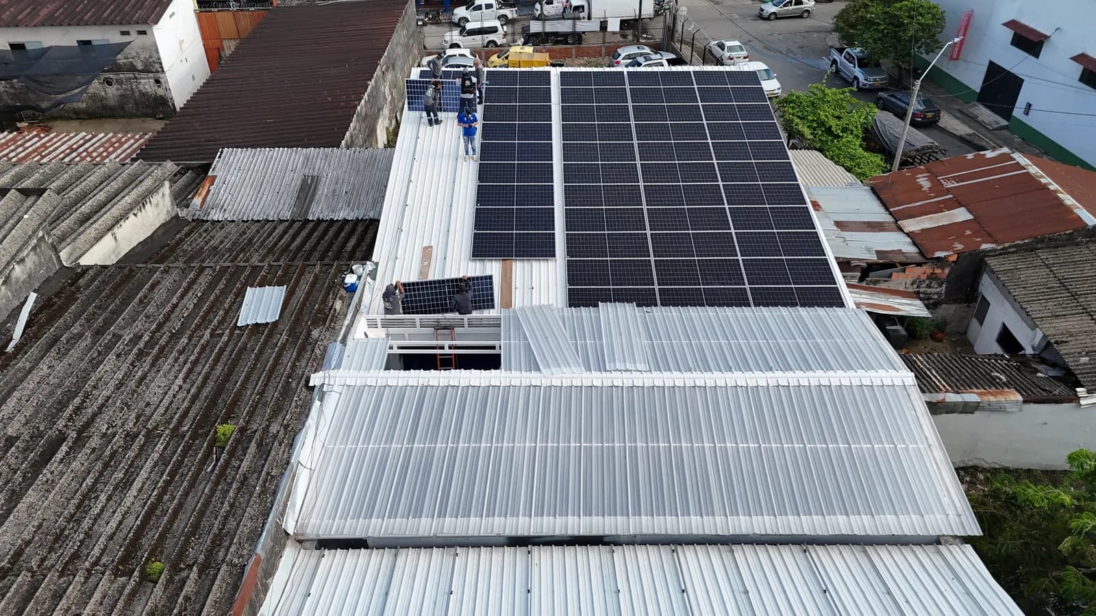 Vista aérea con dron de la cubierta metálica del CDA totalmente ocupada por módulos solares, con la cuadrilla subiendo e instalando los últimos paneles.