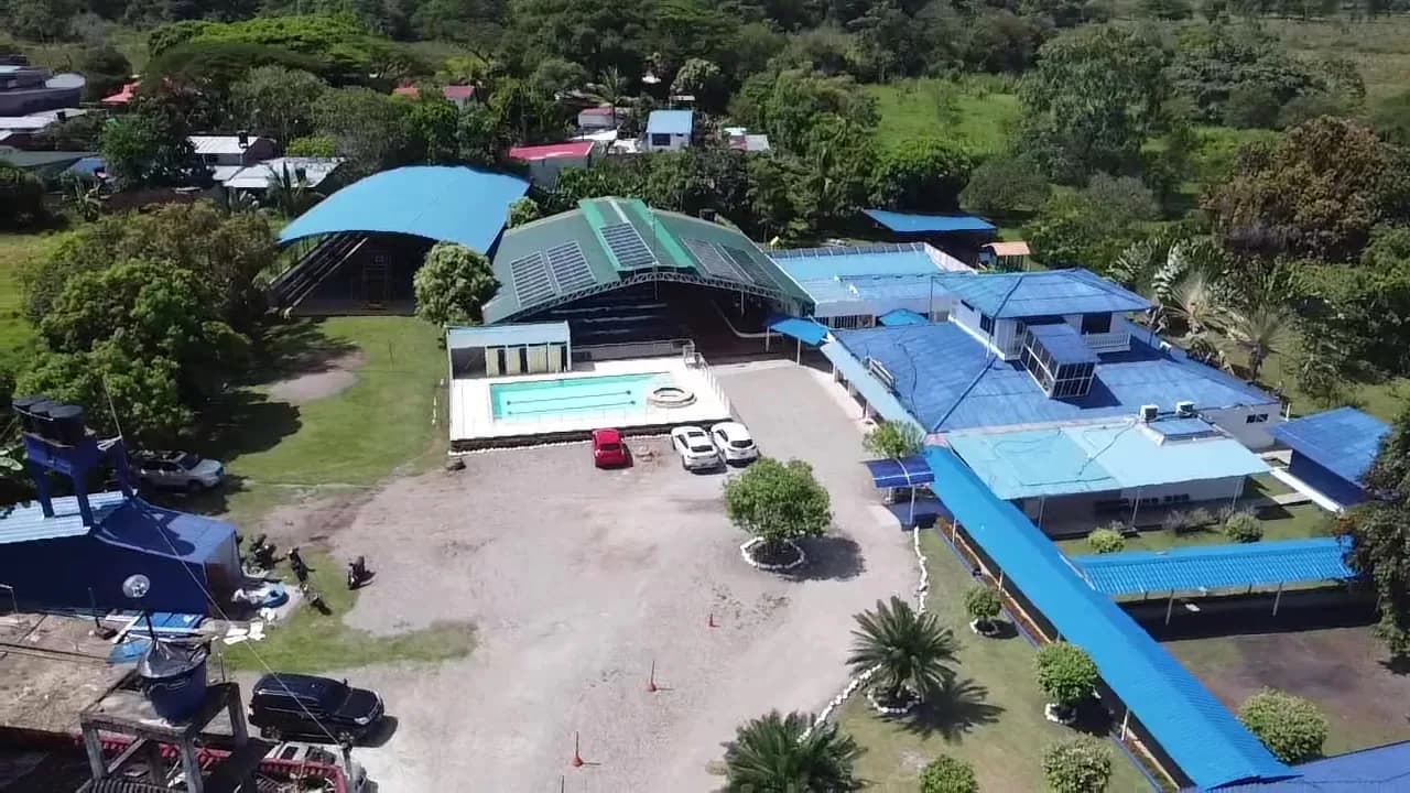Vista aérea de todo el campus del colegio mostrando los módulos solares sobre la cubierta del coliseo y sobre los corredores cubiertos.