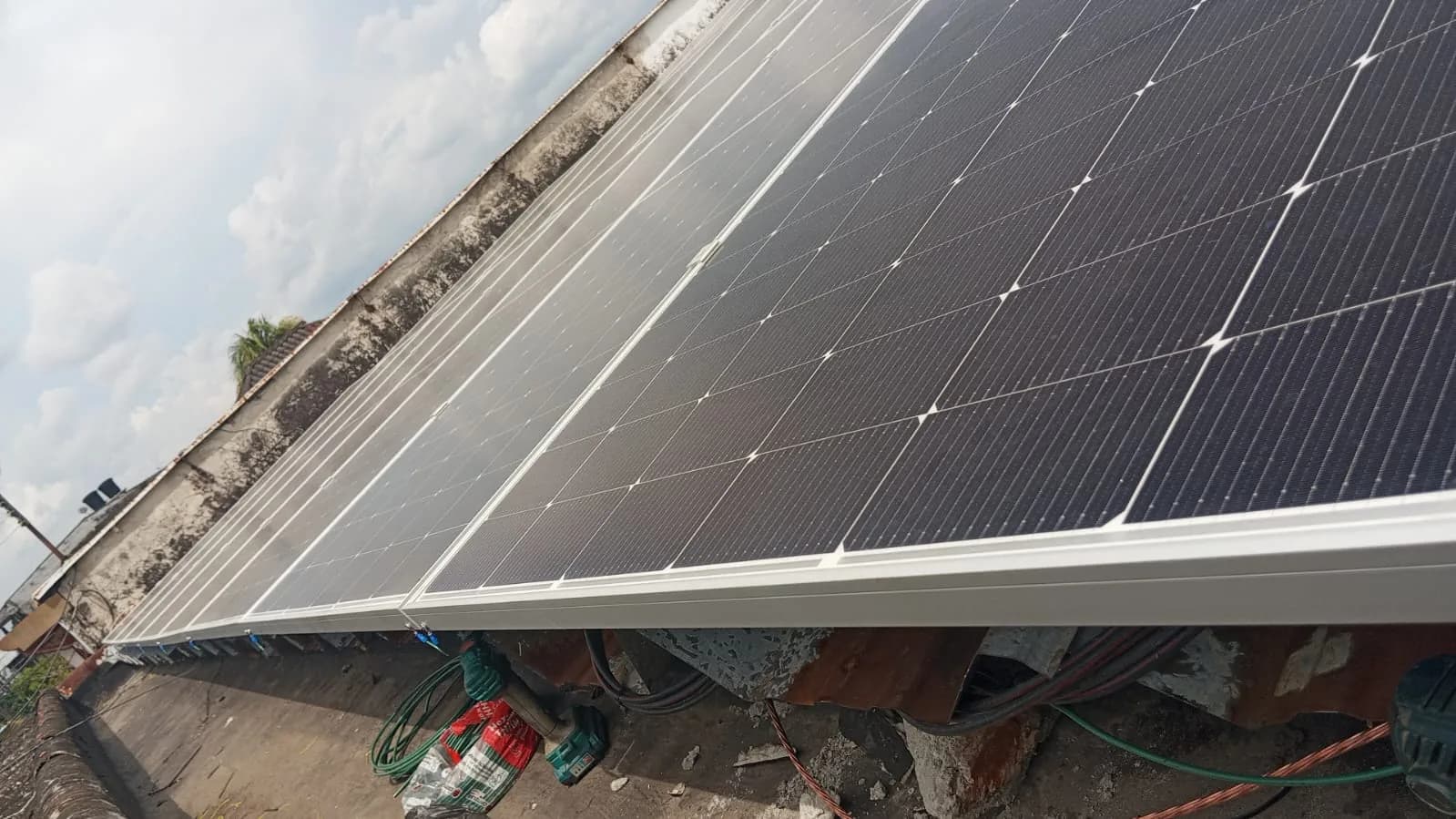 Fila de módulos solares recién instalada sobre la cubierta metálica de la planta, vista a contraluz contra el cielo del atardecer.