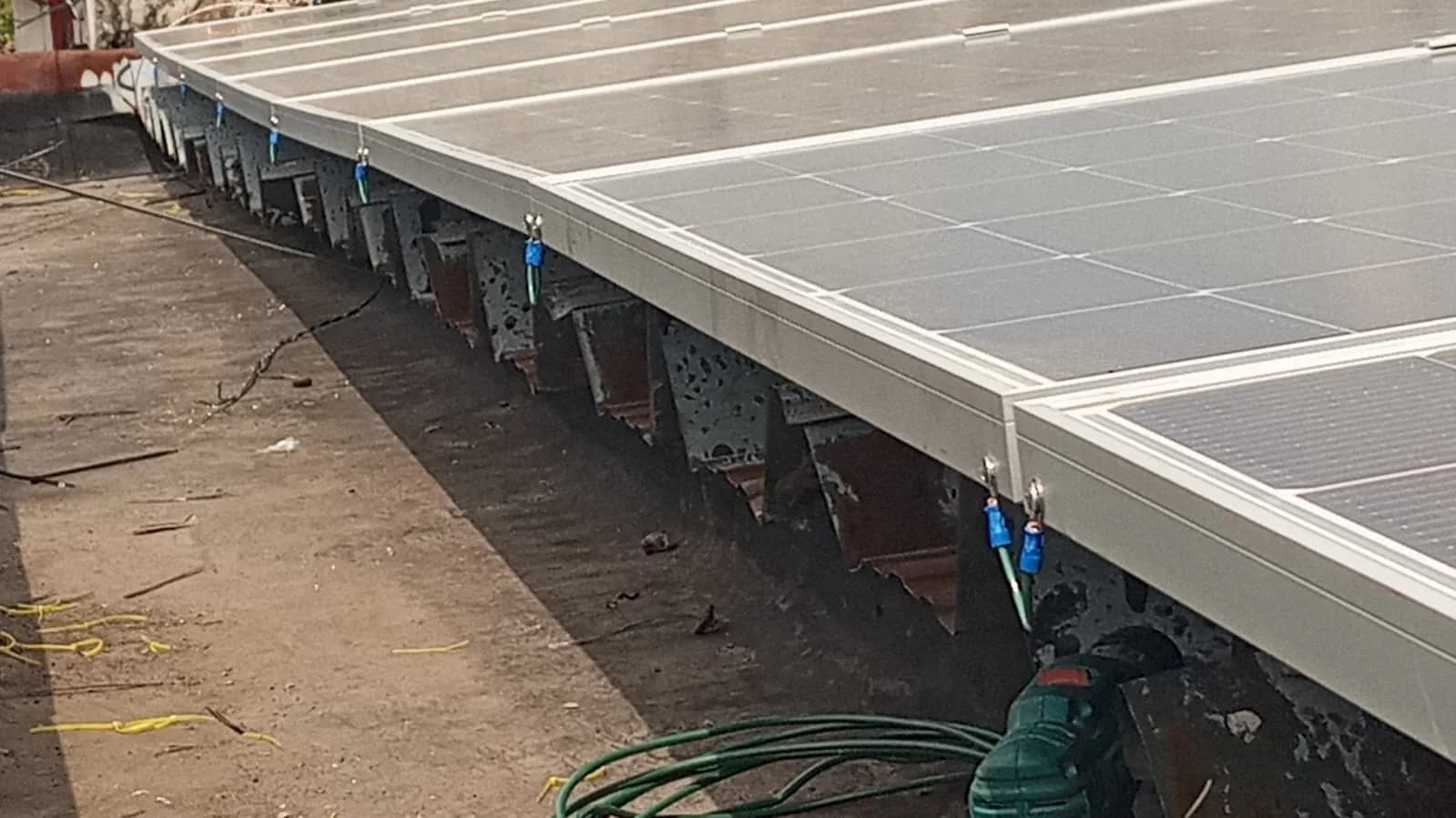 Borde del arreglo fotovoltaico apoyado sobre la estructura metálica de la cubierta, con los cables de puesta a tierra conectados módulo a módulo.