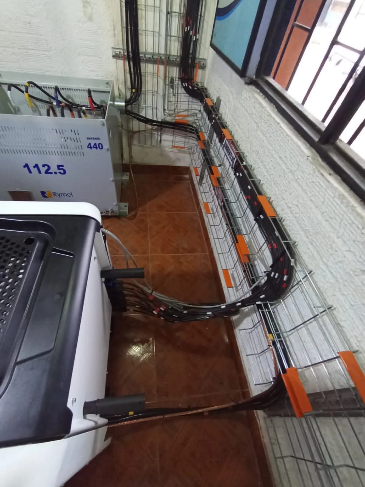 Entradas de string del inversor y su salida hacia el transformador de 112,5 kVA, con las bandejas de piso ordenando y marcando todos los circuitos.