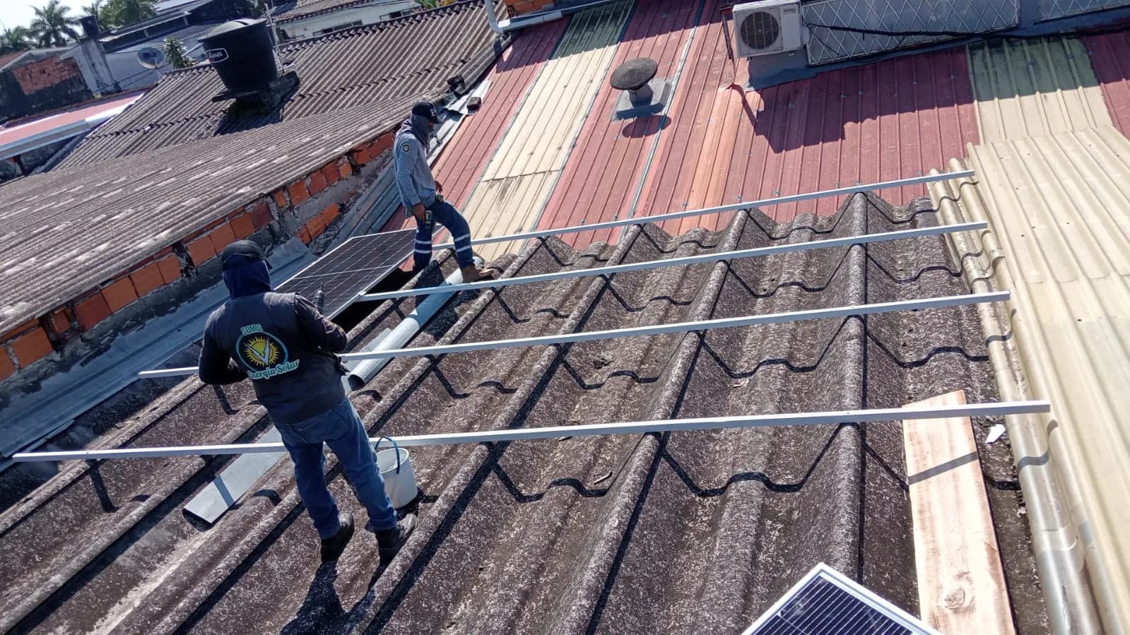 Cuadrilla instalando los rieles de aluminio sobre la cubierta de teja del edificio.