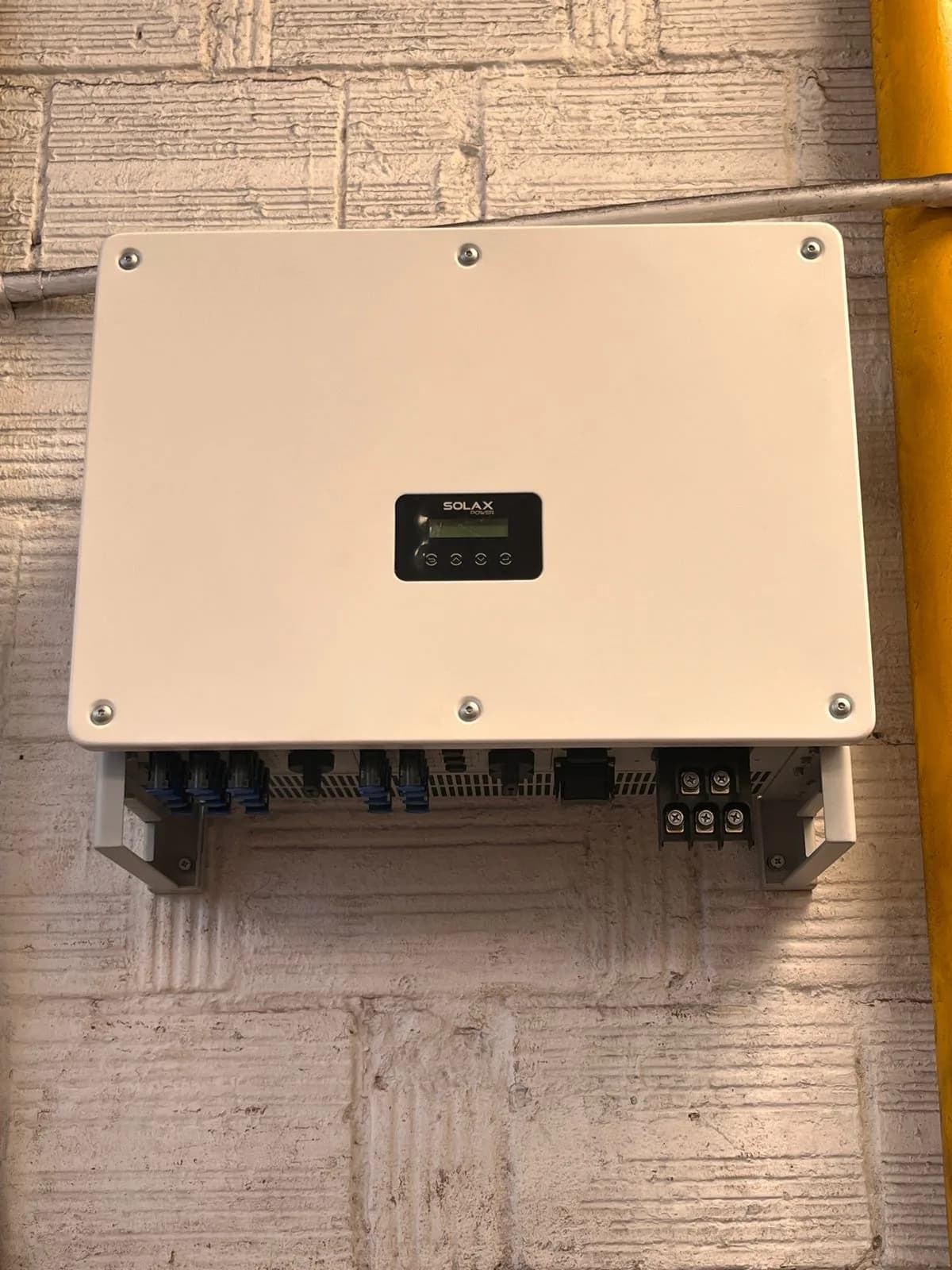 Inversor trifásico SolaX instalado y conectado en el muro del edificio.