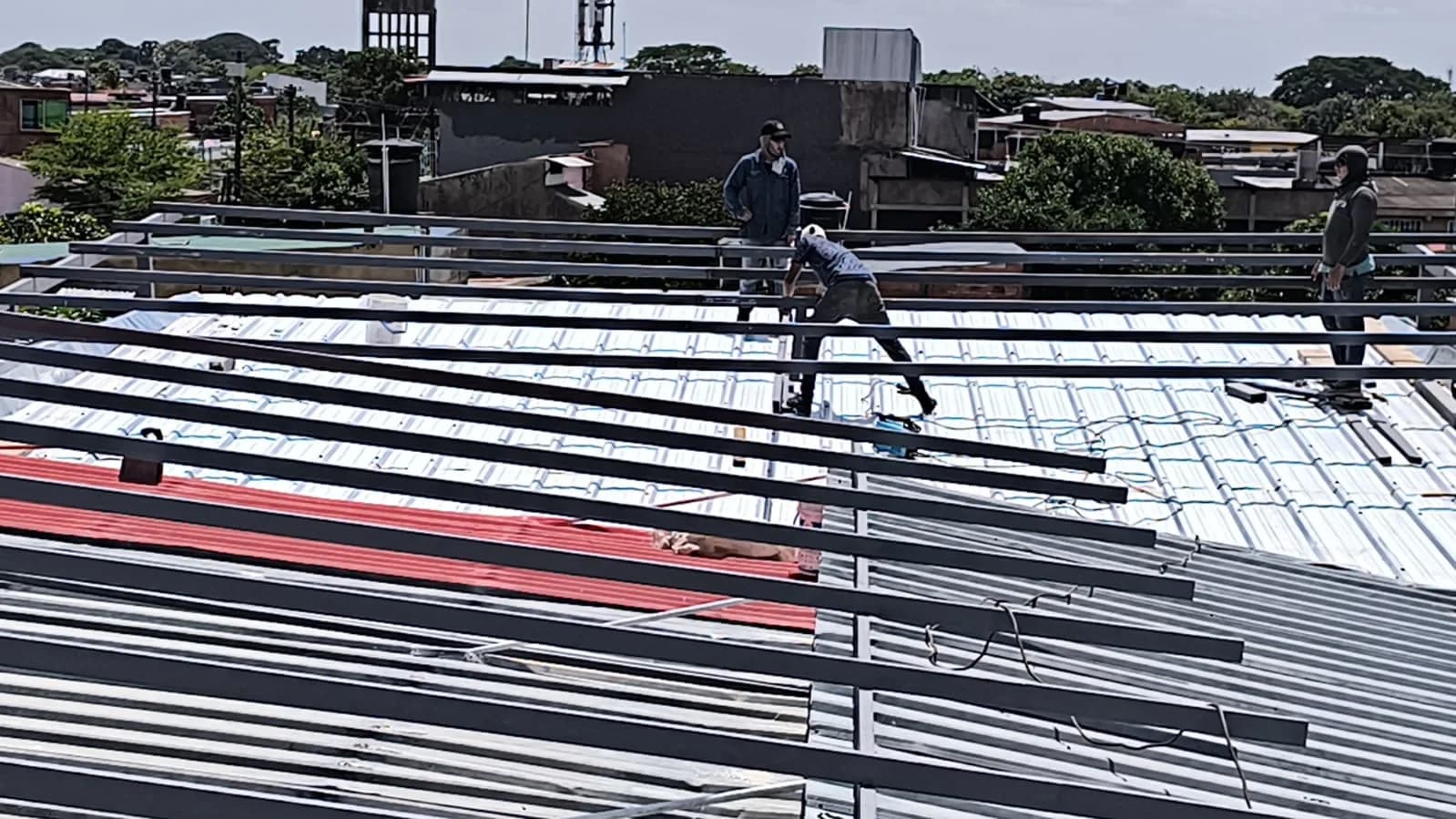 Cuadrilla montando la estructura metálica y las tejas de la cubierta sobre la terraza del hotel.