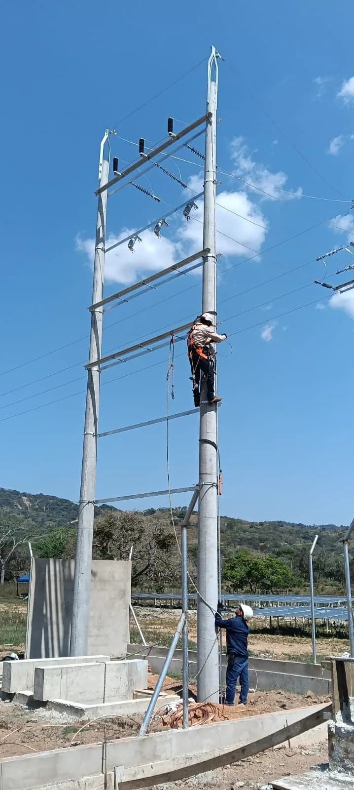 Cuadrilla montando la estructura en H de retención con la granja solar en piso al fondo.