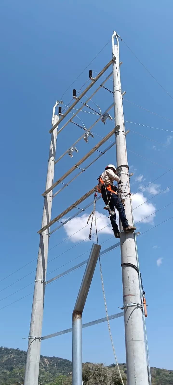 Linero ascendiendo el poste de concreto del pórtico de media tensión.